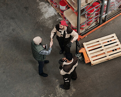 three men standing in a small circle, shaking hands and conversing