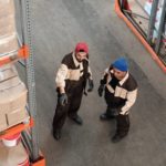 one warehouse worker directing another with his hands