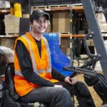 warehouse worker sitting in forklift and smiling