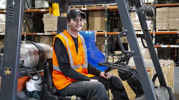 warehouse worker sitting in forklift and smiling