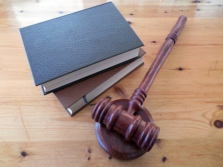 two stacked books lying next to gavel on wooden desk