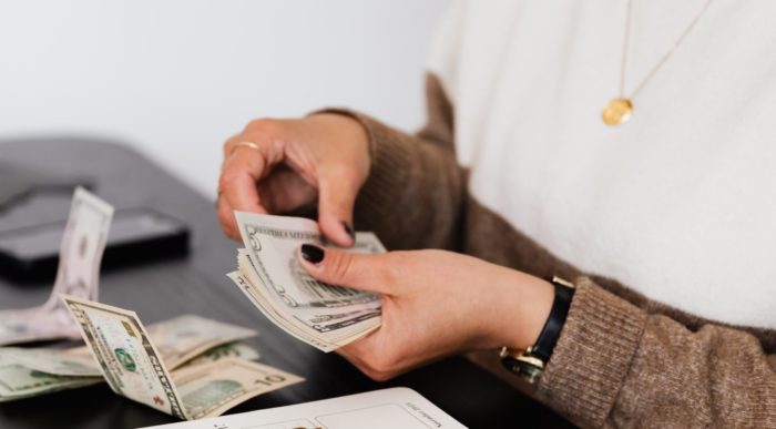 woman holding cash, with more on the table